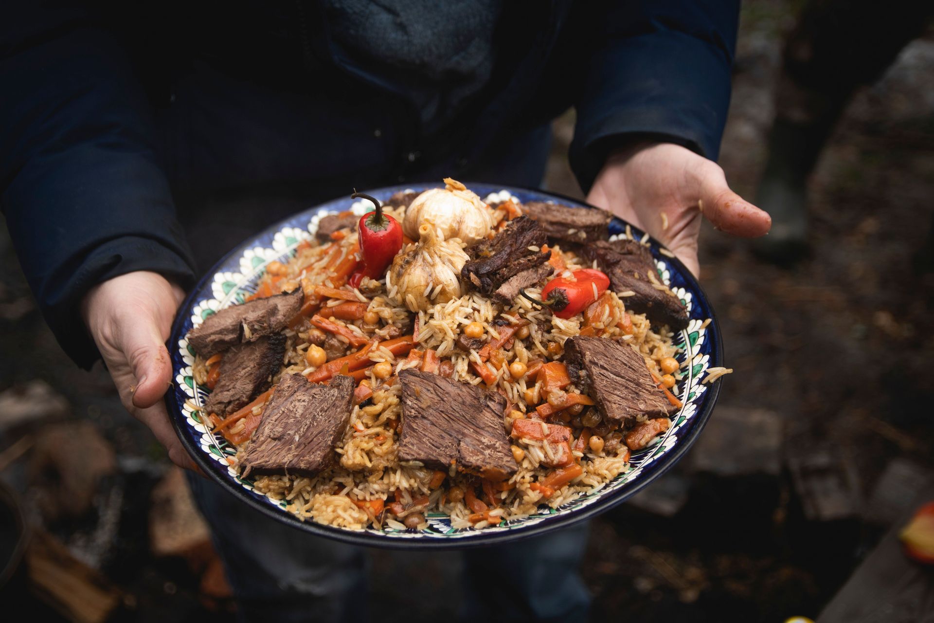 Close-up of homemade plov with meat served outdoors, showcasing vibrant colors and detailed textures.